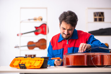 Young male repairman repairing musical instruments at workplace