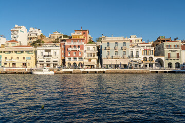 Blick auf den Hafen von Agios Nikolaos auf Kreta, Griechenland, im Hintergrund farbenfrohe Häuser, direkt am Wasser des Hafen gebaut