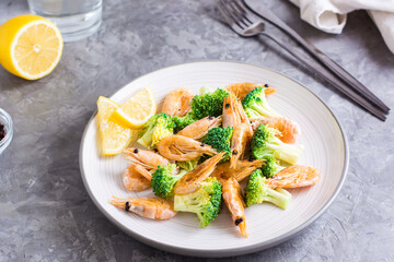 Fried broccoli and shrimp on a plate on the table. Close-up