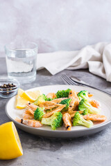 Fried broccoli and shrimp on a plate on the table. Vertical view. Copy space