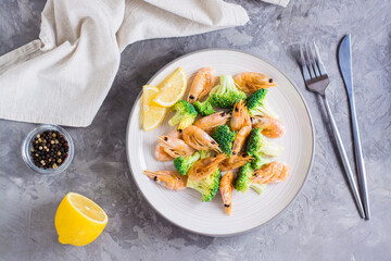 Fried broccoli and shrimp on a plate on the table. Top view