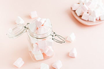 White and pink marshmallows in the form of a heart in a jar and on a plate. Selective focus
