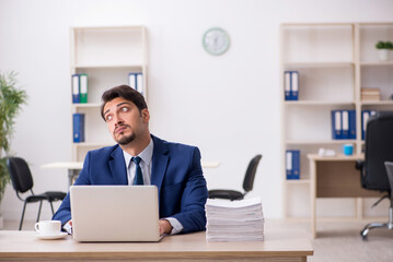 Young male employee and too much work in the office