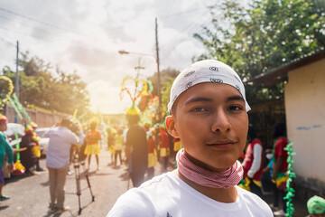 Portrait of a young Latin man looking at the camera participating in a religious festival during...