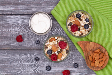 Healthy breakfast with homemade granola with almonds, raspberries and blueberries, yogurt on a wooden rustic table, flat lay
