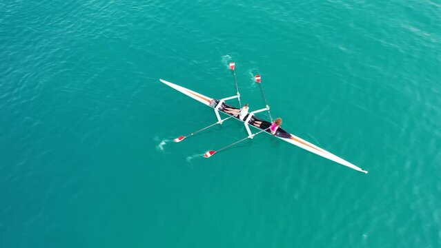 Aerial drone top down video of sport canoe operated by team of young trained women athletes in emerald lake