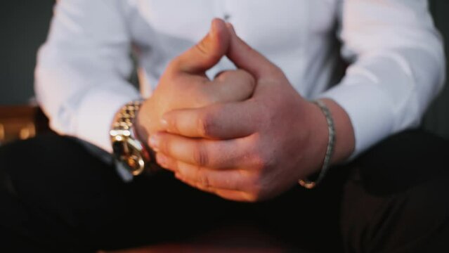 An upset man sits and clenched his fist and taps his other hand on it. Businessman misunderstood partner and angry. Restraining anger. Problems. Negative emotional state.