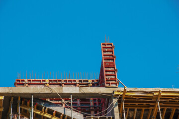 Naklejka premium Formwork and building metal supports are used in the modern construction of load bearing structures of residential buildings against the blue sky.