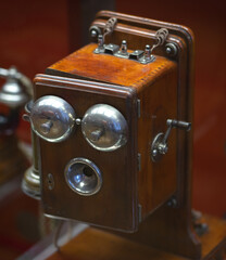 An old telephone made of wood.Square vintage phone with a metal bell.