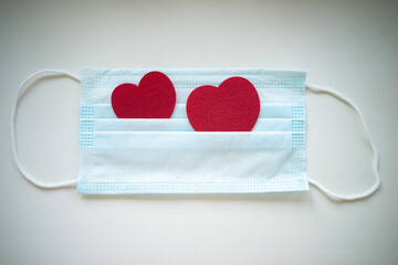 Two hearts made of felt fabric come out of a medical mask. Treatment of the heart. Taking care of the heart.