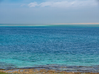 Beautiful coastline at low tide. Blue sea against the blue sky.