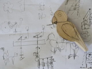 Parrot drawing with a pencil on paper and a wooden figurine of a parrot