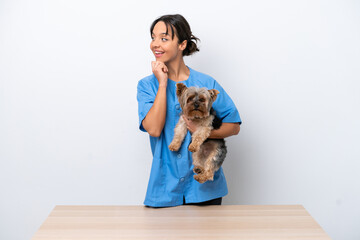 Obraz premium Young veterinarian woman with dog on a table isolated on white background thinking an idea and looking side