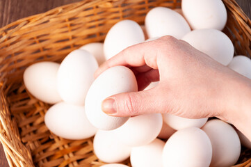 Basket with white eggs. Hand take a egg from basket. White eggs in a wicker basket. Simple...