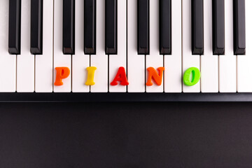 The word Piano is composed of multicolored letters on the piano keys. Copy space.