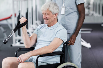 Portrait of smiling senior man using wheelchair in gym during rehabilitation therapy, copy space