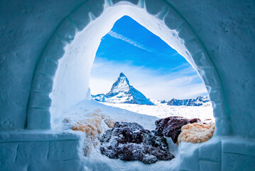 View of Matterhorn peak seen through ice igloo on snowy landscape - obrazy, fototapety, plakaty