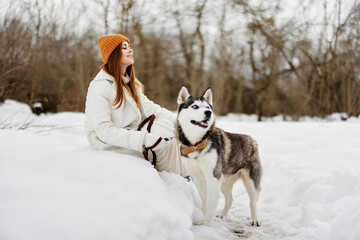 Happy young woman winter clothes walking the dog in the snow Lifestyle