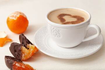 Cup of delicious morning coffee with cinnamon heart, whole orange and orange slice in chocolate
