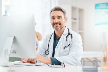 Research is what allows me decide how to best treat patients. Portrait of a mature doctor working on a computer in a medical office.