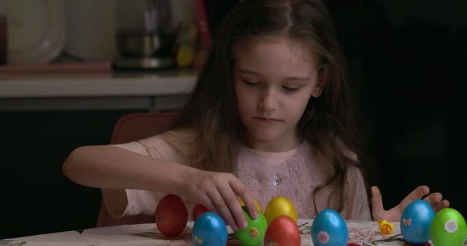 The girl glues decorative stickers on Easter eggs and folds them. Easter eggs, the feast of the passover.