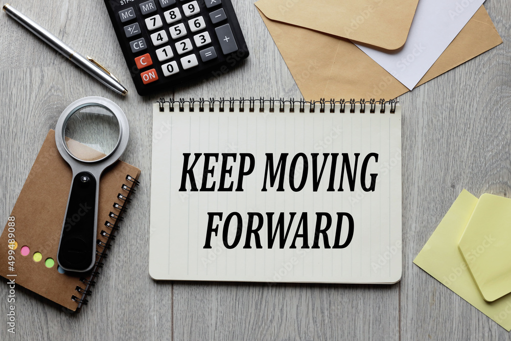 Poster keep moving forward. text on an open notepad. on a wooden background