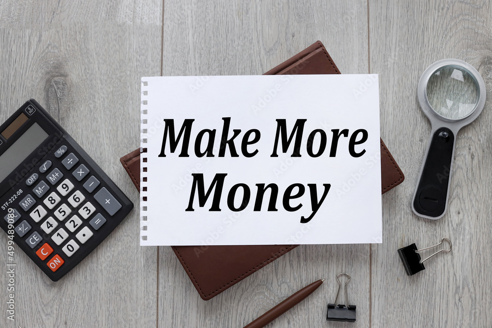 Poster make more money text on an open notepad. on a brown notebook