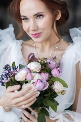 Naklejka premium Beautiful attractive caucasian young woman in a white wedding dress with a bridal flower bouquet. Smiling