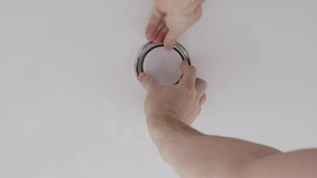 A male electrician changes the light bulbs in the spotlight ceiling lamp