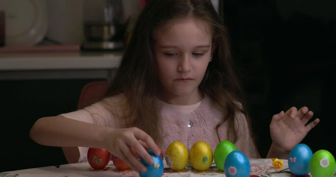 The girl glues decorative stickers on Easter eggs and folds them. Easter eggs, the feast of the passover.