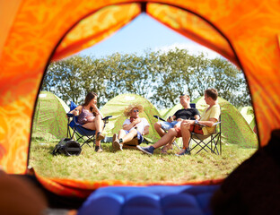 Camping with friends is the best part of this festival. Shot of a group of friends sitting outside...