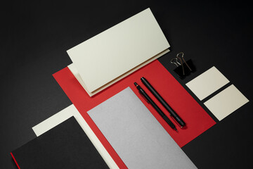 Stationery branding mockup template with red A4 Letterhead, business card, envelope, note bookpencil.  Dark background real photography.