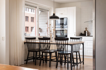 Kitchen facing a balcony. White light interior with black chairs. 