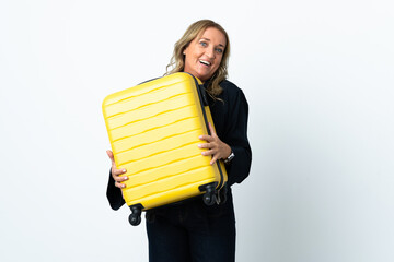 Middle aged blonde woman over isolated white background in vacation with travel suitcase and surprised