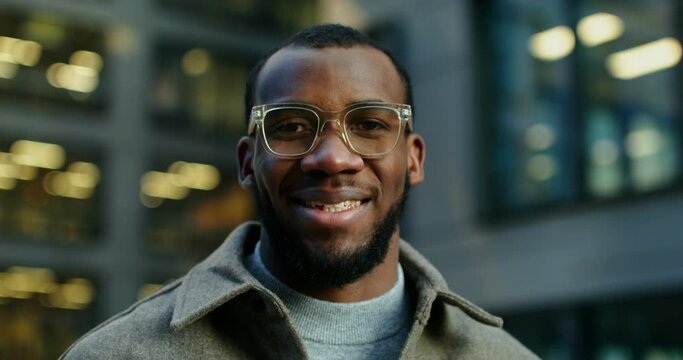 African-American man smiling looking at the camera near a modern building