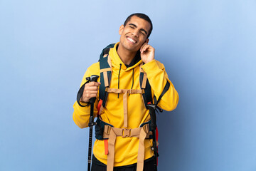 African American man with backpack and trekking poles over isolated background laughing