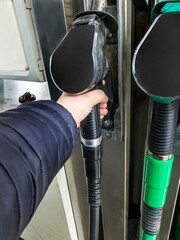 Mans arm holding a diesel fuel pump trigger nozzle, at a filling station,England,United Kingdom.