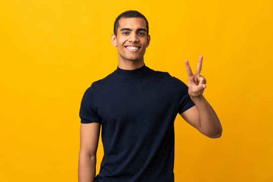 African American man counting numbres over isolated yellow background