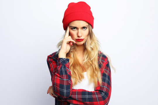 pretty young hipster blonde woman with bright sexy make up wearing stylish urban plaid shirt and red hat
