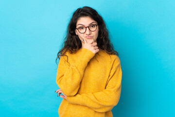 Fototapeta premium Teenager Russian girl isolated on blue background thinking