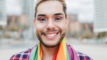 Gay man with makeup on wearing rainbow flag outdoor - LGBTQ drag queen concept - obrazy, fototapety, plakaty