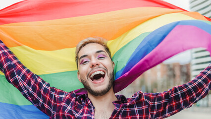 Gay man with makeup on waving rainbow flag outdoor - LGBTQ drag queen concept