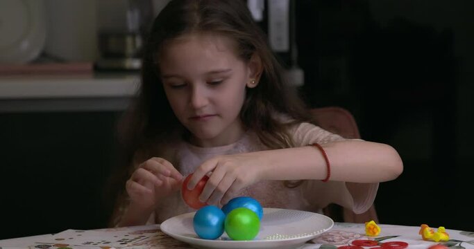 The girl glues decorative stickers on Easter eggs and folds them. Easter eggs, the feast of the passover.