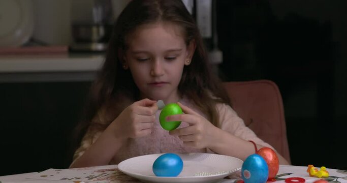 The girl glues decorative stickers on Easter eggs and folds them. Easter eggs, the feast of the passover.