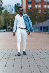 african american man dressed in white walking down the street