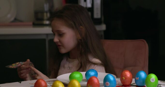 The girl glues decorative stickers on Easter eggs and folds them. Easter eggs, the feast of the passover.