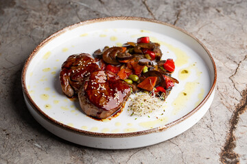 Grilled meat fillet steak wrapped in bacon medallions with raspberry sauce, served with vegetables and mushrooms