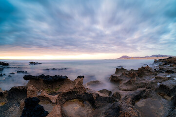 Sunrise on the beach with rocks and warm colors on the Canary Island of Fuerteventura