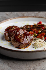 Grilled meat fillet steak wrapped in bacon medallions with raspberry sauce, served with vegetables and mushrooms