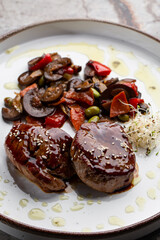 Grilled meat fillet steak wrapped in bacon medallions with raspberry sauce, served with vegetables and mushrooms